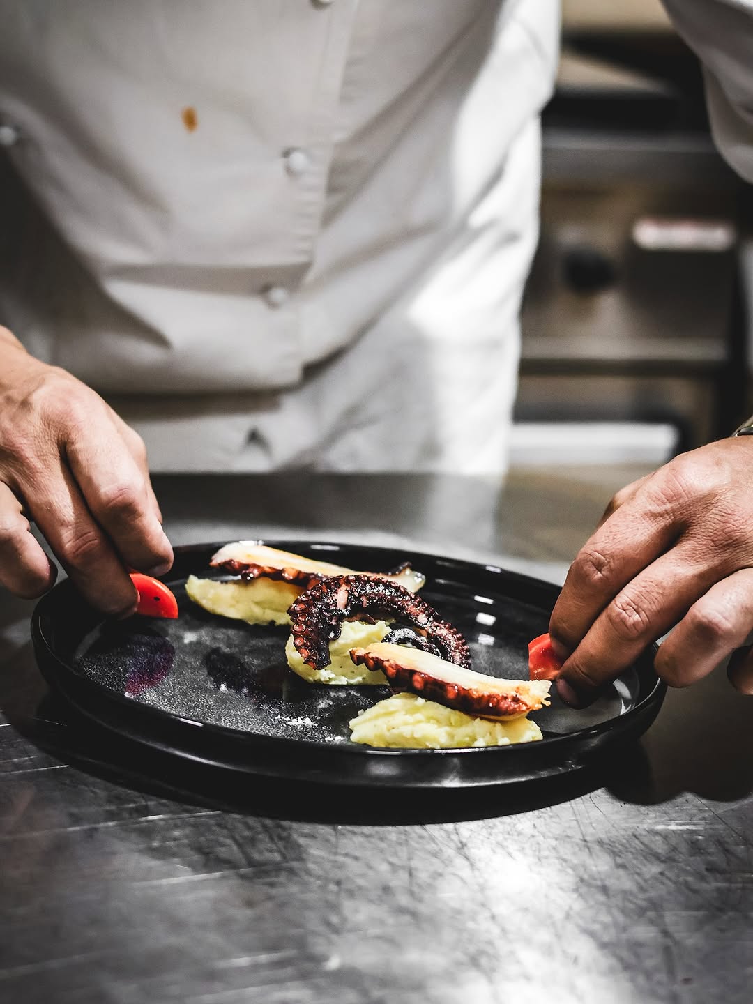 Kamarier duke prezantuar pjatë frutash deti me logon CLANDESTINO.