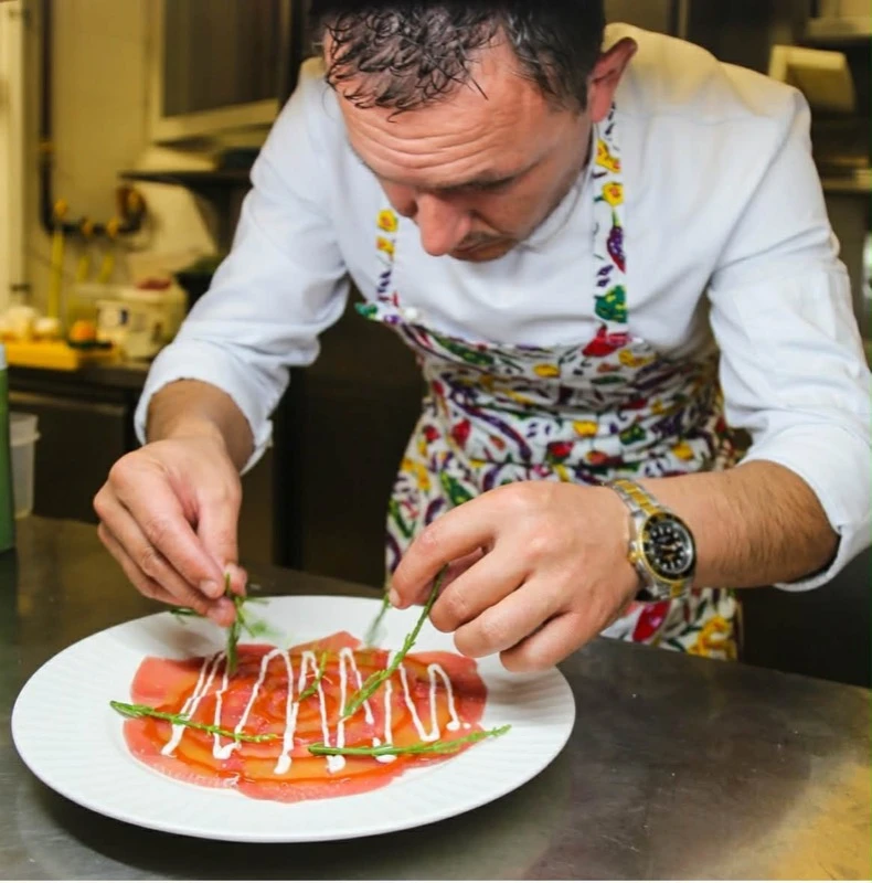 Shefi duke dekoruar karpaqo salmon me krem dhe barishte