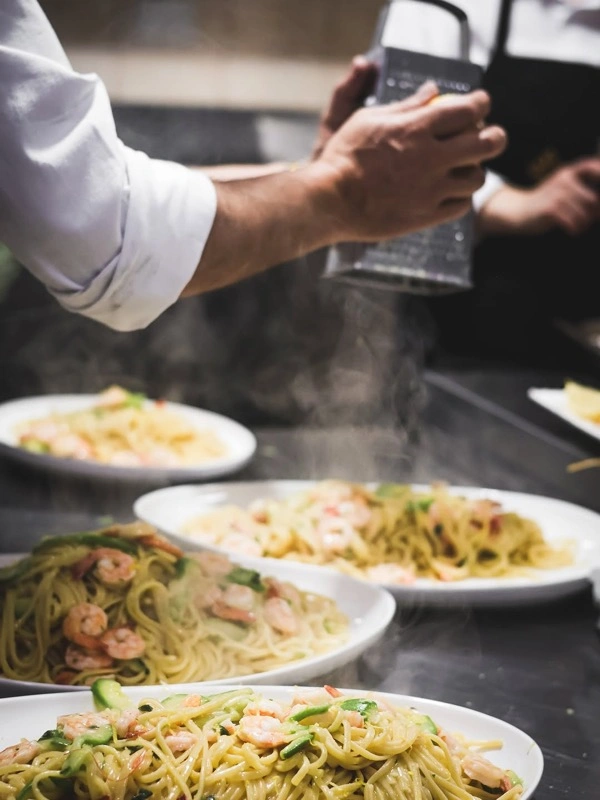 Shefi duke shtuar djathë mbi pasta