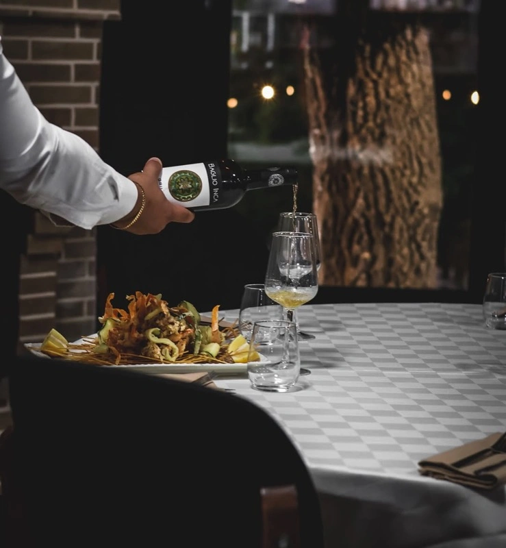 Verë e bardhë e derdhur pranë pjatës me fruta deti